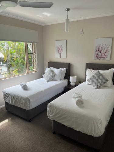 two beds sitting in a room with a window at Reef Terraces on St Crispins in Port Douglas