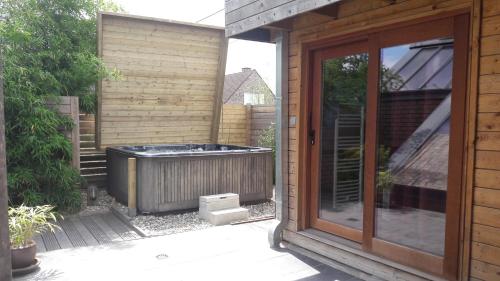 una bañera de hidromasaje fuera de una casa con una puerta corredera de cristal en B&B Aquavert & Wellness, en Tournai
