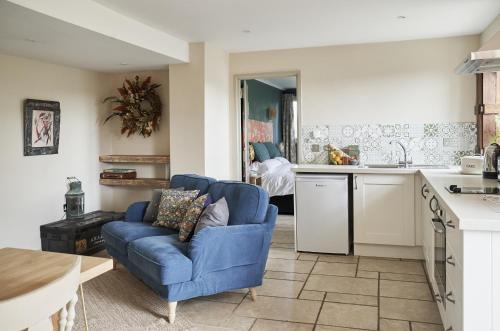 a living room with a blue couch and a kitchen at The Cottages at Launceston Farm in Blandford Forum