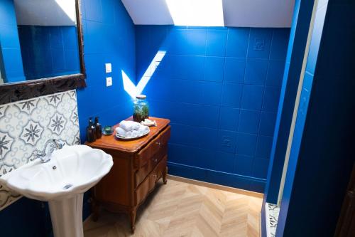 een badkamer met een wastafel en een blauwe muur bij v i o l e t t e La souris des champs in Étival-Clairefontaine
