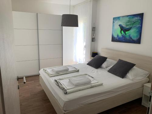 1 dormitorio con 1 cama blanca y una pintura en la pared en Apartment Sunrise, en Vinjerac