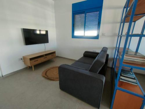 a living room with a couch and a television at Desert Path in Beʼer Ora