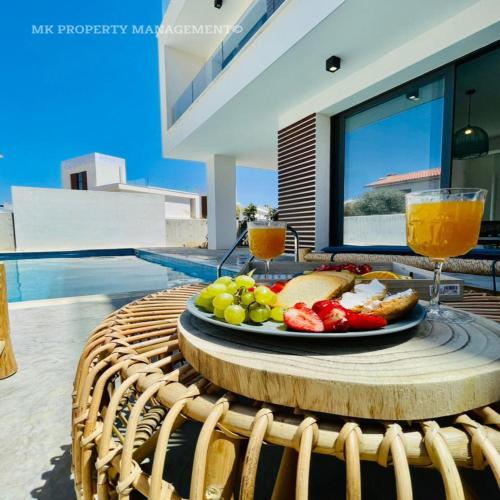 a plate of food on a table with a glass of orange juice at By the Beach Villa 7 in Protaras