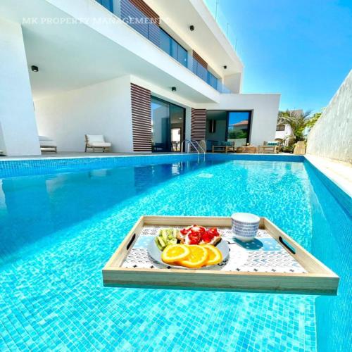 a tray of fruit on a table in a swimming pool at By the Beach Villa 7 in Protaras