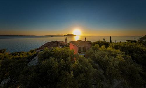 a house on the shore of a lake with the sunset at Anatoli Apartments in Marathias
