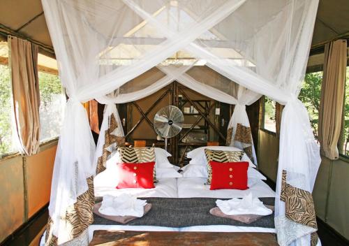 a bedroom with a canopy bed with red pillows at Khowarib Lodge in Khowarib