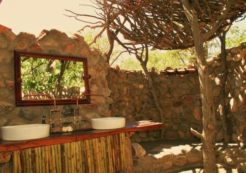 a stone bathroom with two sinks and a tree at Khowarib Lodge in Khowarib
