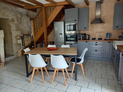 a kitchen with a wooden table and white chairs at Troglo Bel Être in Langeais