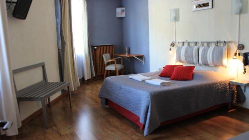 a bedroom with a bed with red pillows and a chair at Hôtel Des Alliés in Pont-dʼAin