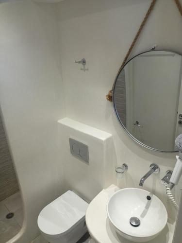 a white bathroom with a sink and a mirror at Naxos Illusion Nikos Verikokos in Naxos Chora