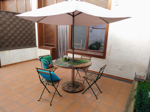 a table and chairs with an umbrella on a patio at Las Gemelas 1 y 2 apartamentos turísticos in Cardeñosa