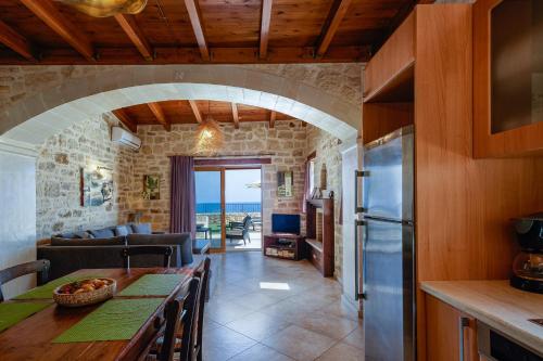 a kitchen and living room with a table and a refrigerator at Stavromenos Villas - Private Pools & Seaview - 500m from Beach in Stavromenos