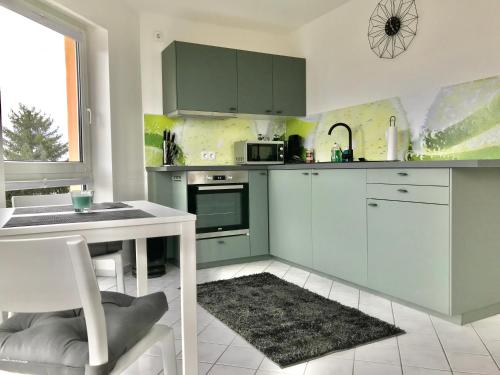 a kitchen with green cabinets and a table and a sink at Helles und ruhiges Apartment direkt am Flughafen Leipzig Halle in Schkeuditz