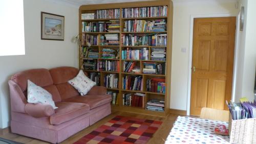 a living room with a couch and a book shelf filled with books at Hopewell self-catering in Gravesend