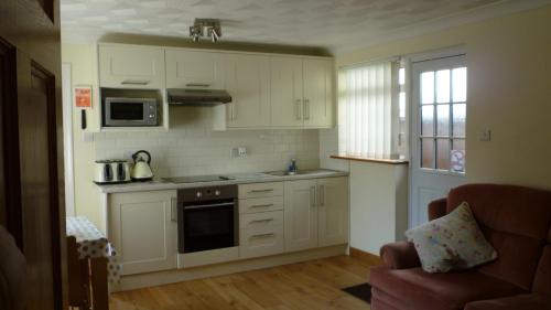 a kitchen with white cabinets and a stove top oven at Hopewell self-catering in Gravesend