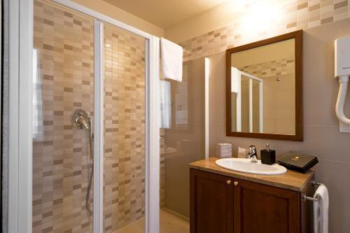 a bathroom with a sink and a shower with a mirror at Cora Hotels Leon d'Oro in CastellʼArquato