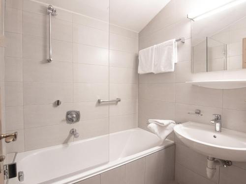a white bathroom with a tub and a sink at La Tombola Appartements in Gerlos