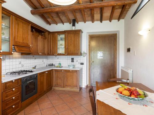 a kitchen with wooden cabinets and a bowl of fruit on a table at Apartment Ciliegio by Interhome in Monsanto
