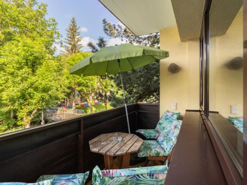 a table and chairs on a balcony with an umbrella at Apartment Haus Grani by Interhome in Zell am See