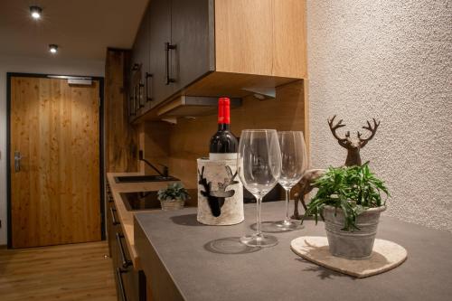 a bottle of wine and two wine glasses on a kitchen counter at Brunnenhof Oberstdorf - Ferienwohnungen mit Hotel Service in Oberstdorf