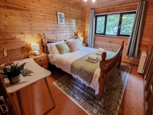 a bedroom with a bed in a log cabin at Wnion Wood Lodge with log burner & sauna in Snowdonia in Llanfachreth