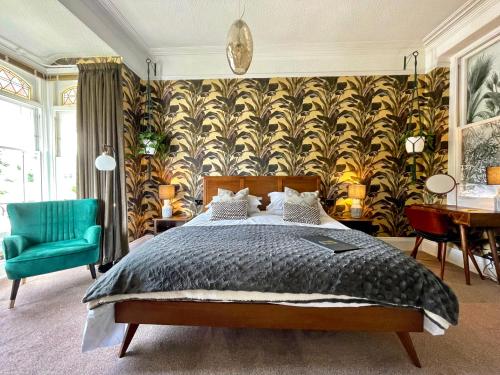 a bedroom with a bed and a green chair at The Earlsdale Bed and Breakfast in Ilfracombe