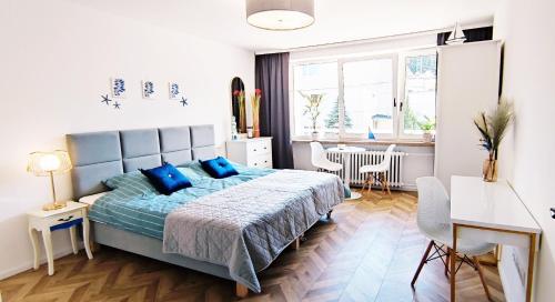 una camera da letto con un letto con cuscini blu e un tavolo di Kapitan Marina Gdynia Rental Apt a Gdynia
