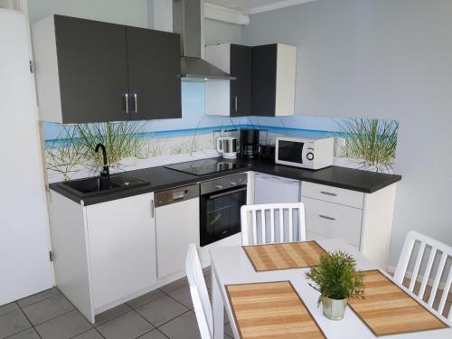a kitchen with white cabinets and a table with chairs at Holiday Home Tossens-3 by Interhome in Butjadingen OT Tossens