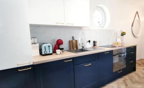 - une cuisine avec des placards bleus et un évier dans l'établissement Kapitan Marina Gdynia Rental Apt, à Gdynia