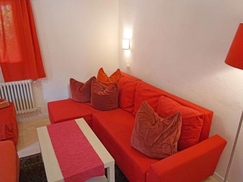 a living room with an orange couch with pillows at Apartment Föhrenheim - SFE202 by Interhome in Leutasch