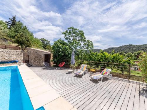 a deck with a swimming pool and chairs next to a house at Holiday Home Chaud'abri by Interhome in Venterol