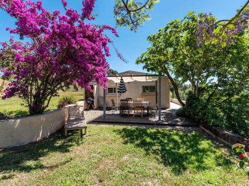 a view of the backyard of a house with a tree with purple flowers at Holiday Home Maison Gerard by Interhome in Cervione