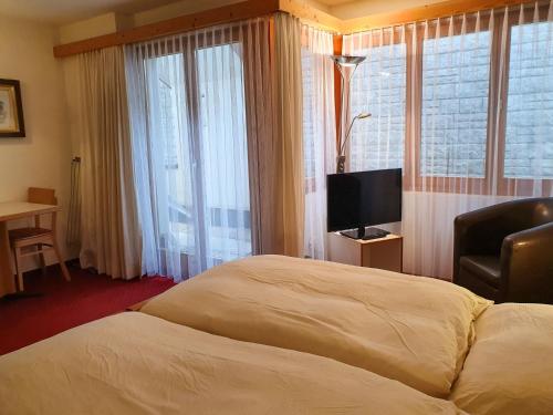 グリンデルワルトにあるApartment Chalet Abendrot-2 by Interhomeのベッドとテレビが備わるホテルルームです。