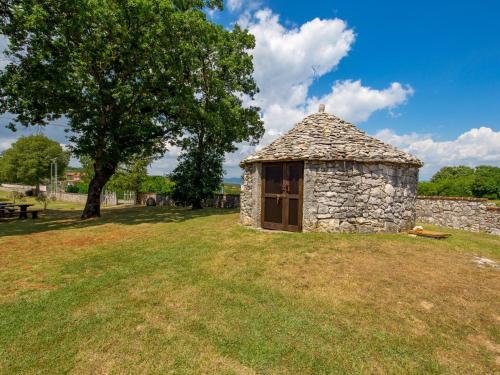 a small stone building in a field with a tree at Holiday Home Diana by Interhome in Kršan