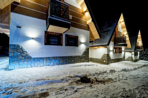 a building covered in snow with lights on it at Komfortowe domki na wynajem - Holiday Tatry in Poronin