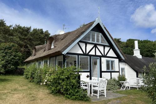 a white house with a roof with a table and chairs at Melsted Badehotel in Gudhjem