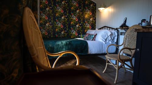 a bedroom with a bed and two chairs at Loch Lomond Waterfront Luxury Lodges in Balmaha