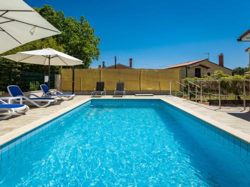 a swimming pool with chairs and an umbrella at Holiday Home Verbanac - LBN351 by Interhome in Labin