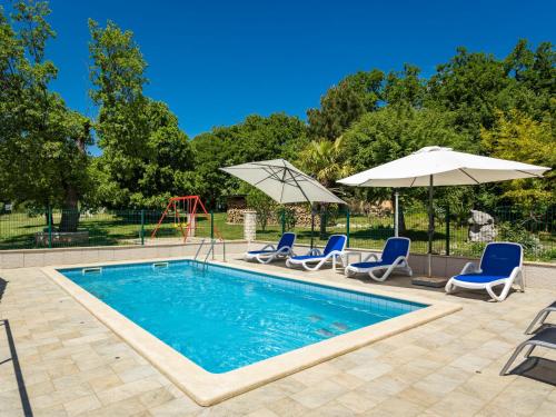 a pool with chairs and umbrellas and a playground at Holiday Home Verbanac - LBN351 by Interhome in Labin