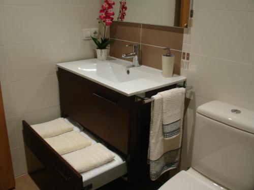 Un baño con lavabo y un inodoro con toallas. en Playa y Montaña Faura-Valencia, en Faura