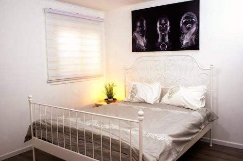 1 cama blanca en un dormitorio con una foto en la pared en שמילה אירוח 2 en Arad