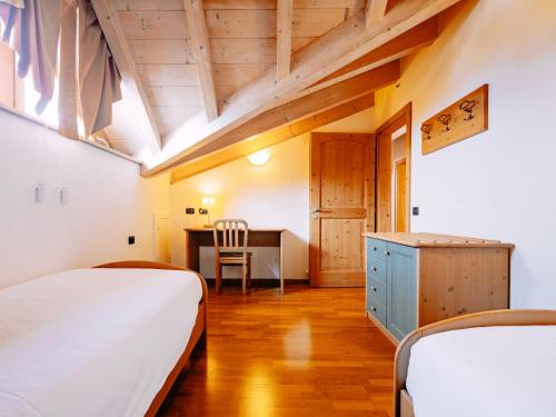 a bedroom with two beds and a desk and a table at Apartment Pensione Villa Belfiore-2 by Interhome in Ronzone