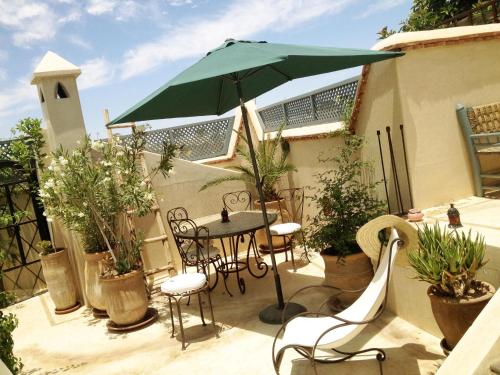 马拉喀什Riad of The Light的一个带桌子和遮阳伞的庭院