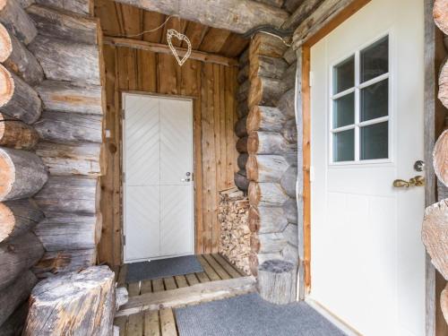 uma porta para uma cabana de madeira com uma parede de pedra em Holiday Home Lomaylläs maja-keloluppo by Interhome em Ylläsjärvi