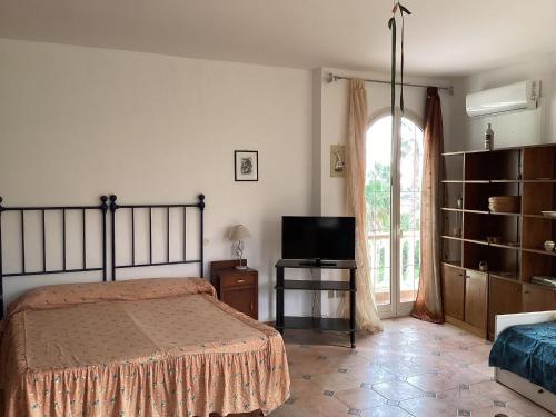 a bedroom with a bed and a tv and a window at Apartment Rotondo by Interhome in Santa Domenica