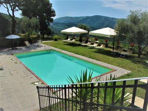 a swimming pool with lounge chairs and umbrellas at Holiday Home Chiesa by Interhome in Linari