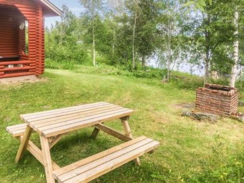 a wooden picnic table in the grass next to a cabin at Holiday Home Koivuranta by Interhome in Petäjävesi