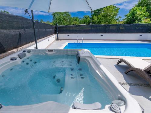 a hot tub with an umbrella next to a swimming pool at Holiday Home Susanne by Interhome in Gorica