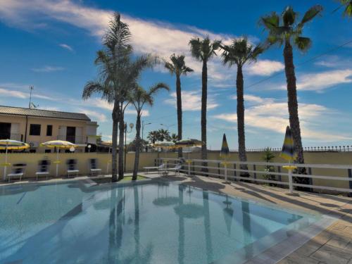 Una piscina con palmeras y una valla. en Apartment L'Ancora-1 by Interhome, en Porto Empedocle