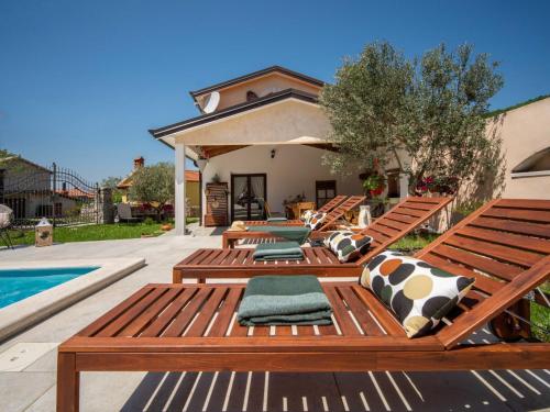 a patio with wooden benches next to a swimming pool at Holiday Home Villa KIM by Interhome in Brest